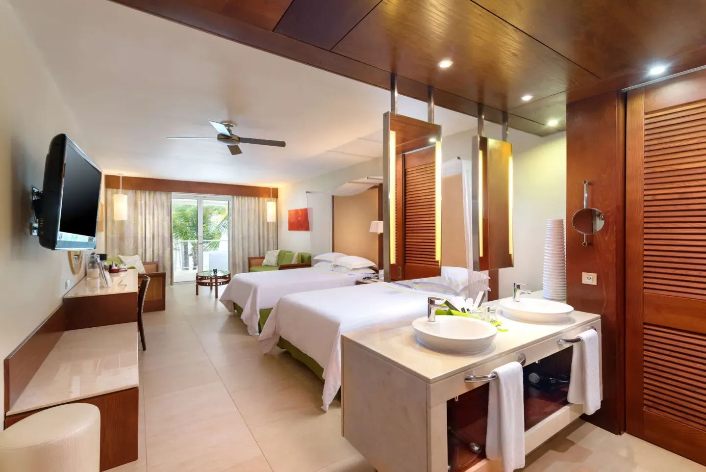 Junior Suite with two beds, double sinks, wall TV, desk, and balcony seating at Barceló Bávaro Palace.
