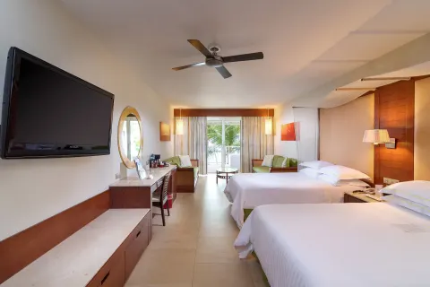 Junior Suite with two beds, wall TV, sitting area, and balcony doors at Barceló Bávaro Palace.