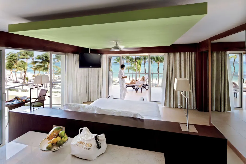 Sea view suite with king bed, terrace loungers, and ocean at Barceló Bávaro Palace.