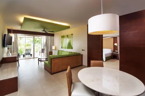 Sea View Suite living room at Barceló Bávaro Palace with green sofa, dining table, and bedroom doorway.