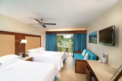 Superior Room with two beds, sofa, desk, and wall TV at Barceló Bávaro Palace.