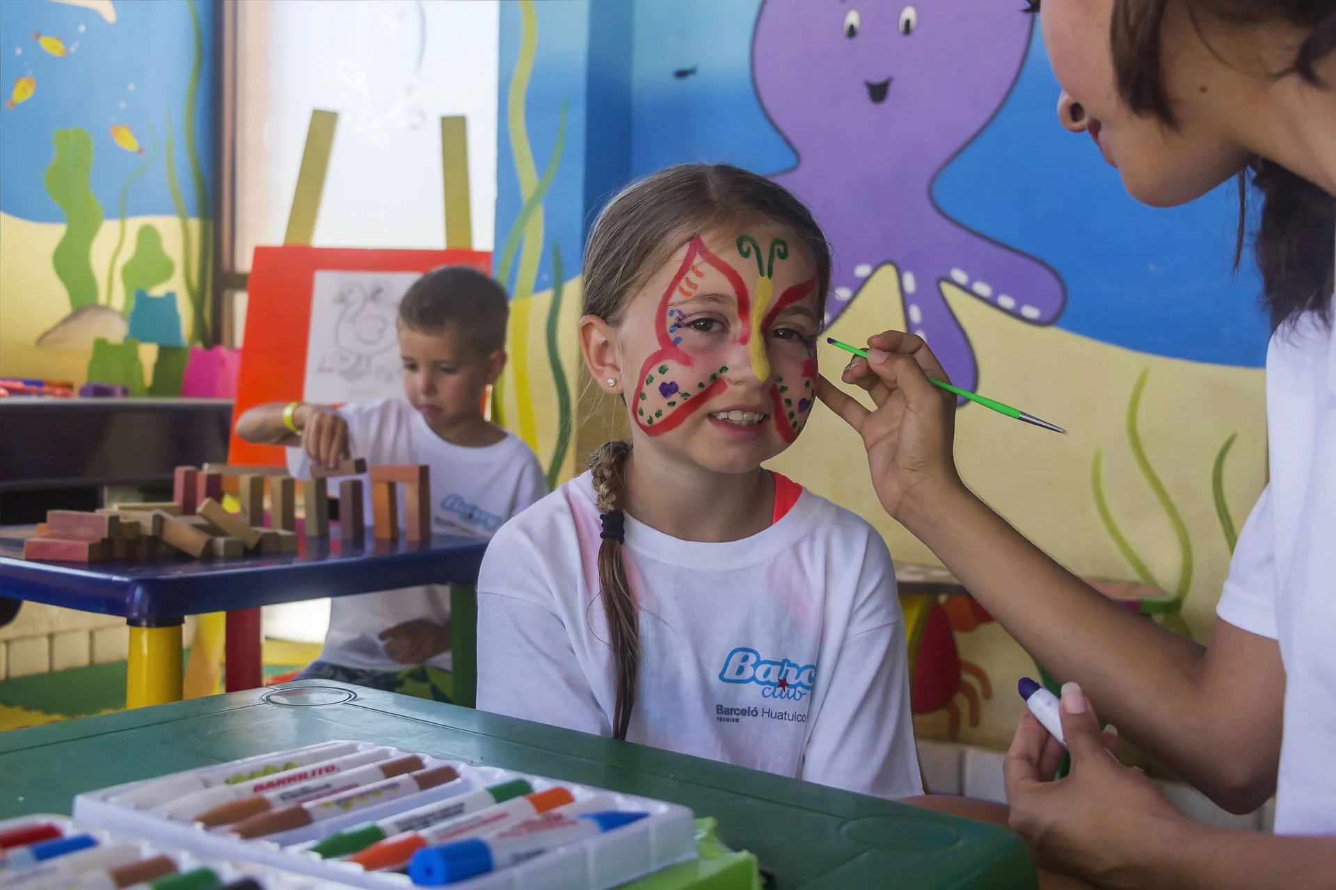 Child has face paint applied in the kids' activity room at Barceló Huatulco.