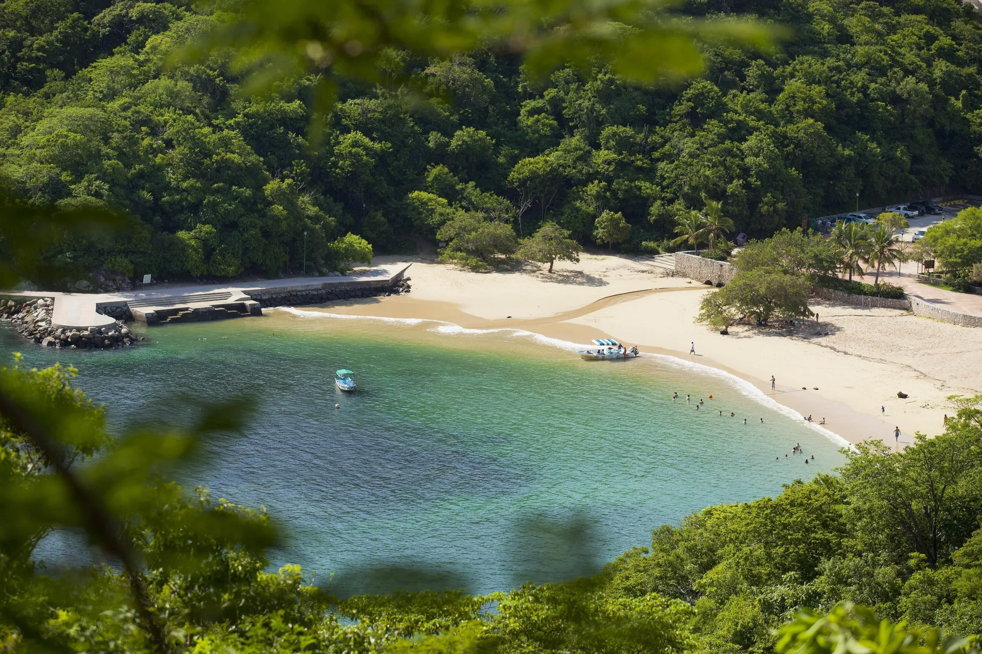 High view of a sheltered cove with swimmers and small boats at Barceló Huatulco.