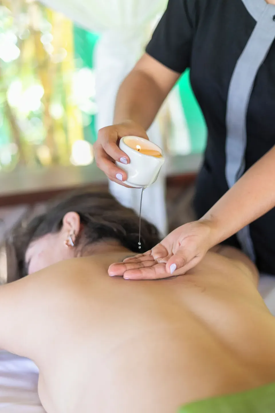 A spa therapist pours warm oil for a back massage at Barceló Huatulco.