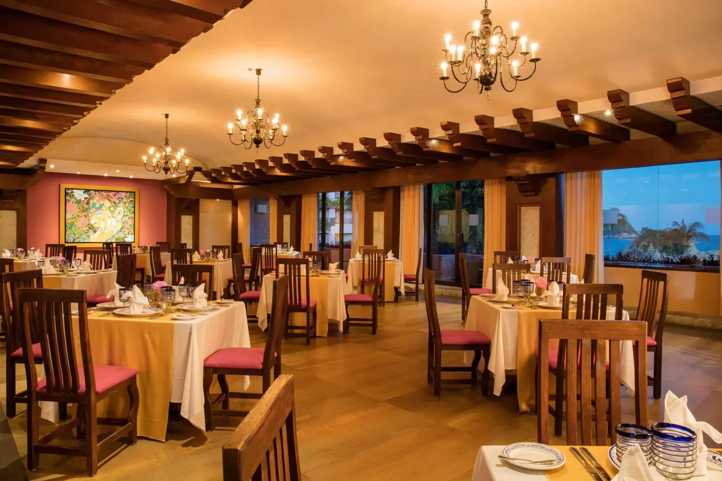 Elegant dining room with chandeliers and ocean-facing windows at Barceló Huatulco.