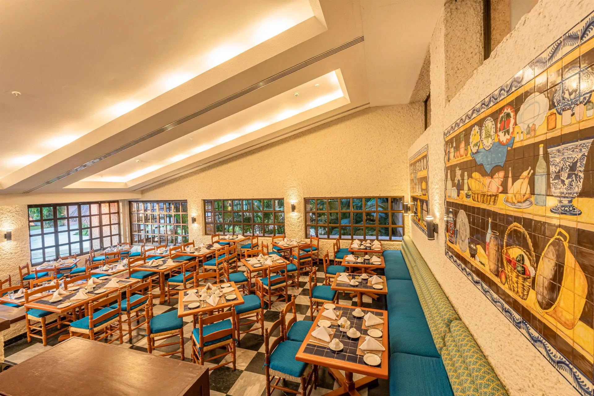Casual dining room with blue seating and tile murals at Barceló Huatulco.