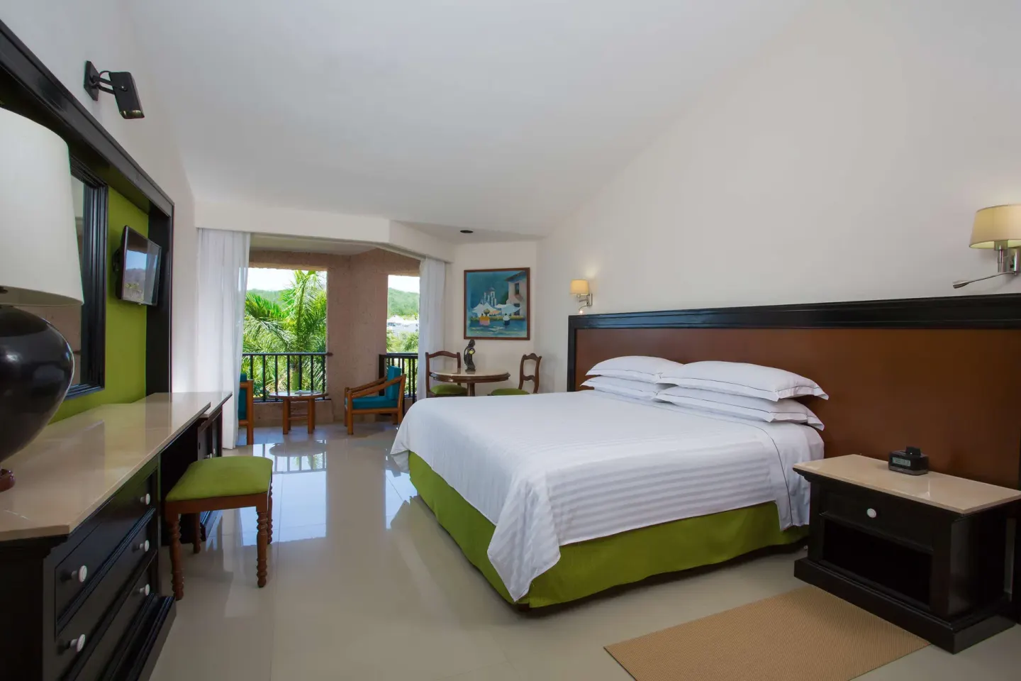 Deluxe Garden View king room with dresser, balcony, and greenery at Barceló Huatulco.