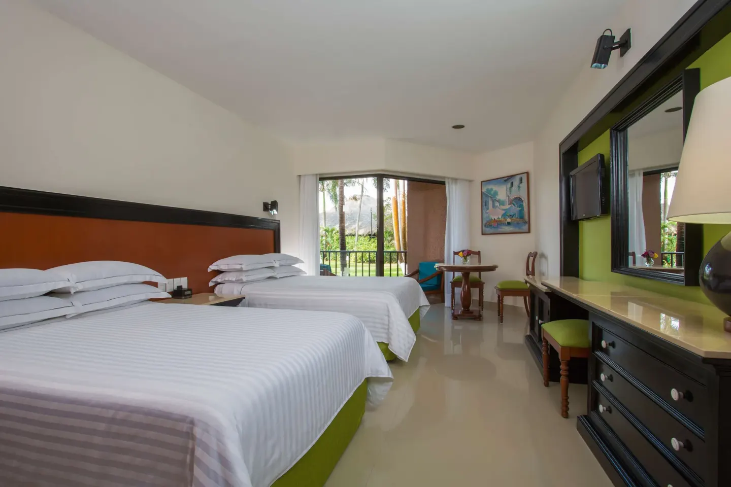 Deluxe Garden View room with two beds, dresser, and balcony greenery at Barceló Huatulco.