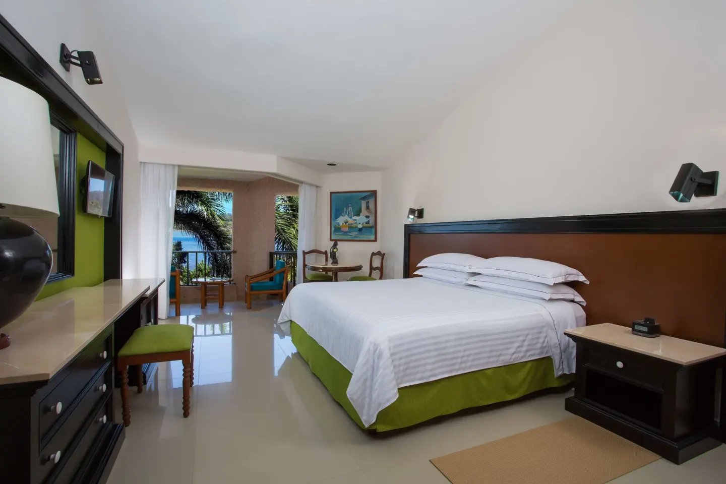 Deluxe Partial Ocean View king room with balcony and palm-framed water view at Barceló Huatulco.