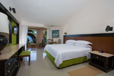 Deluxe Partial Ocean View king room with balcony and palm-framed water view at Barceló Huatulco.