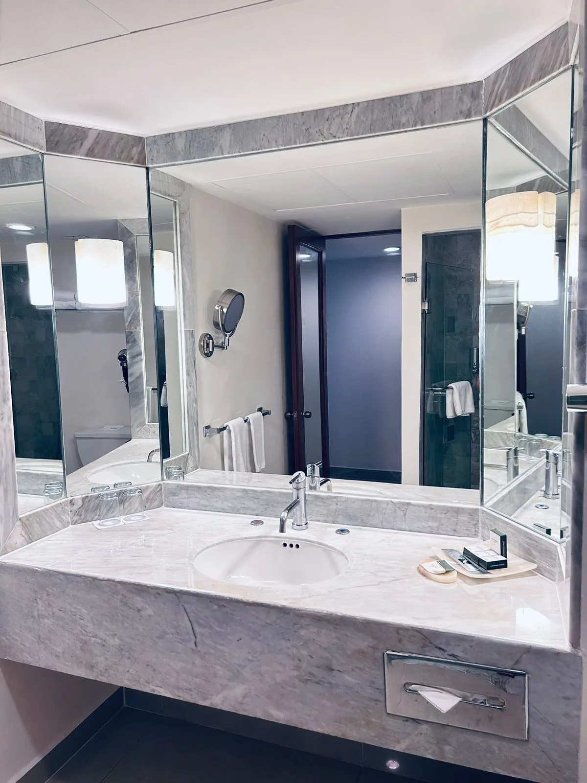 Deluxe Room bathroom at Barceló Huatulco with marble vanity, mirrors, sink, and towels.
