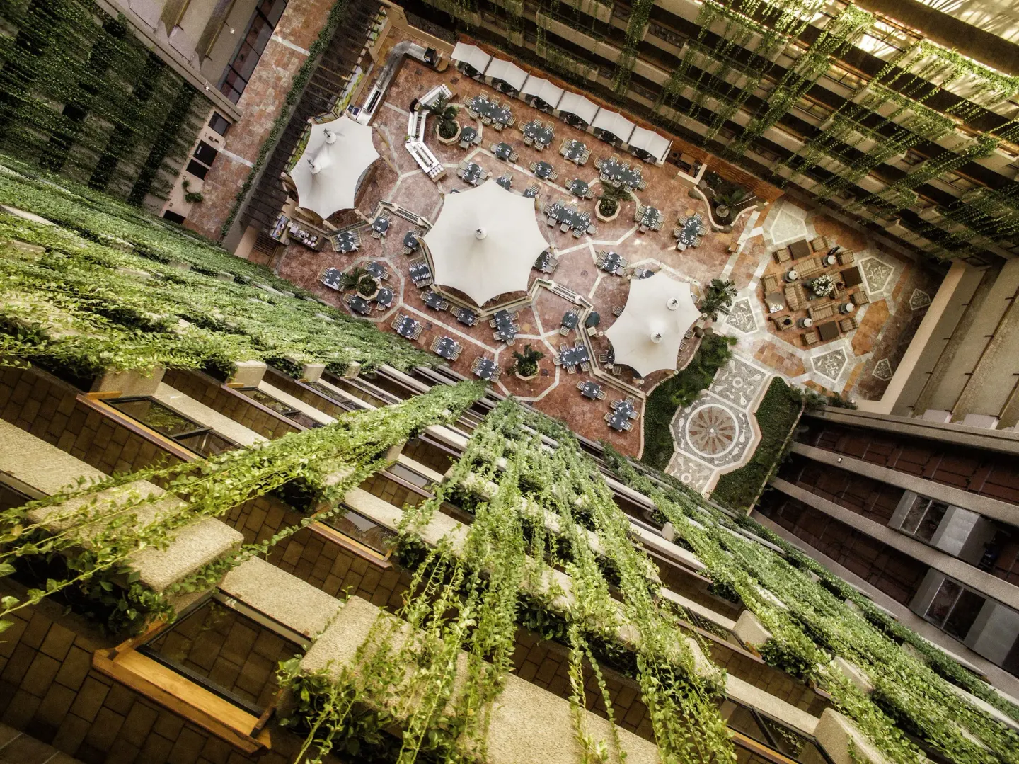 High atrium view of vine-covered balconies and courtyard tables at Barceló Ixtapa.