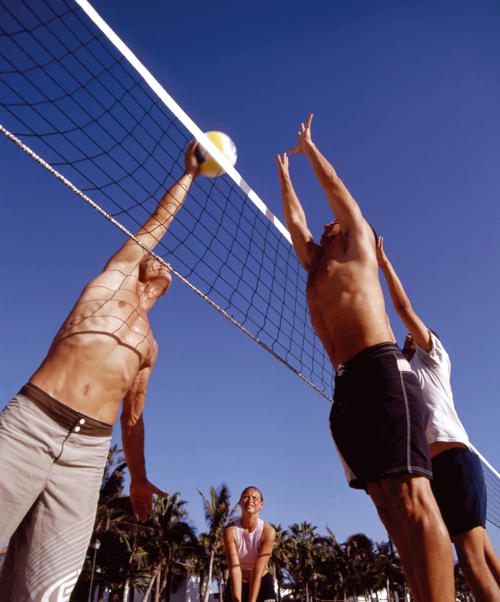Beach volleyball players jumping at the net under blue sky at Barceló Ixtapa.