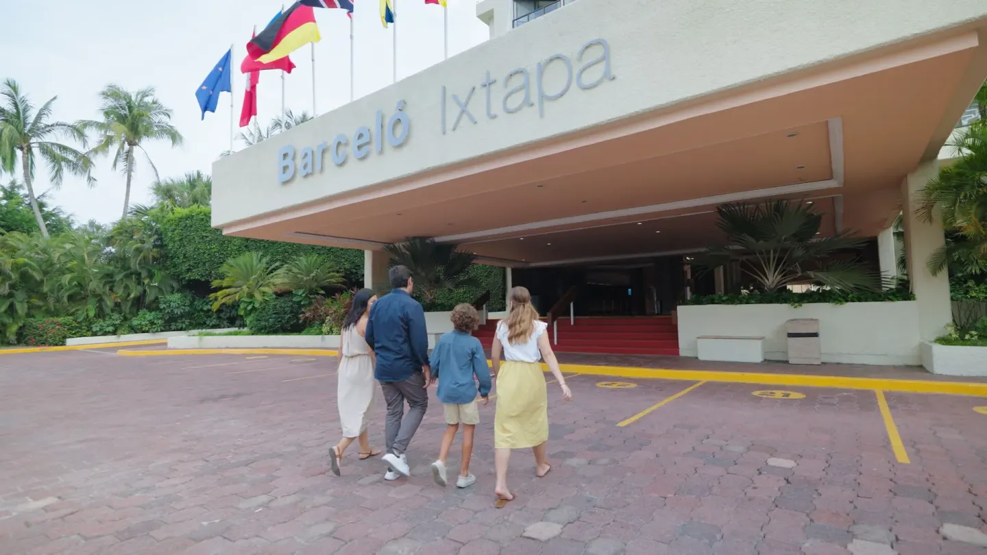Family walking toward the covered entrance under the Barceló Ixtapa sign.