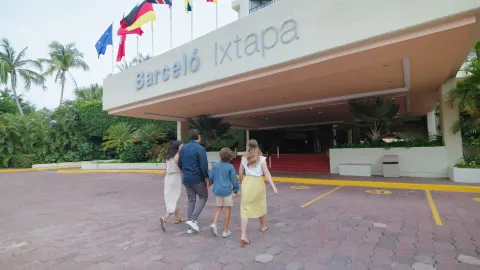 Family walking toward the covered entrance under the Barceló Ixtapa sign.