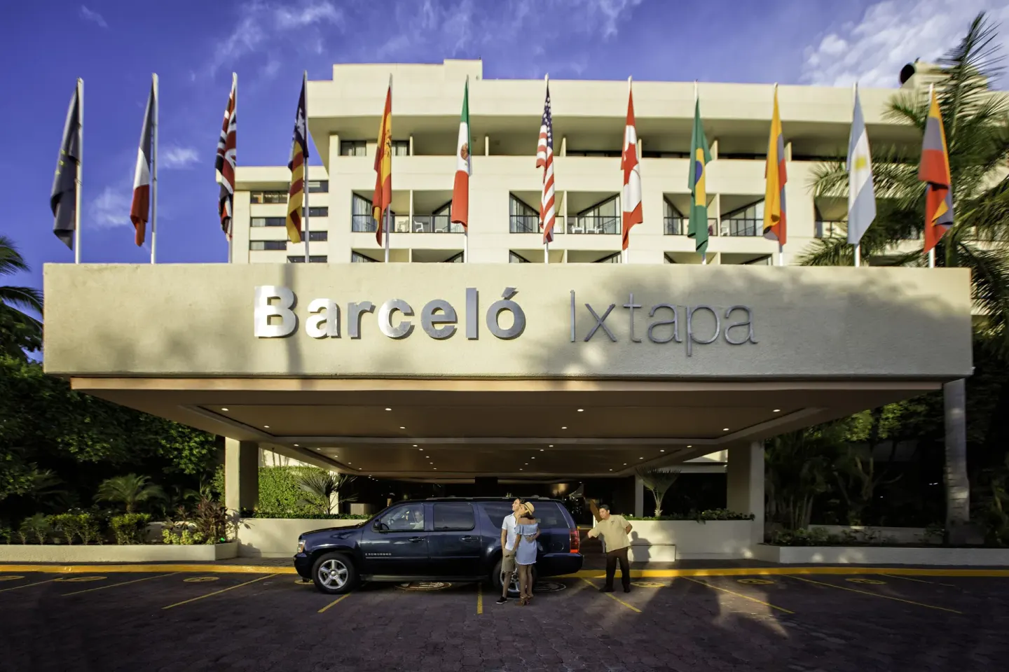 Main entrance canopy with flags and Barceló Ixtapa sign above arriving guests.