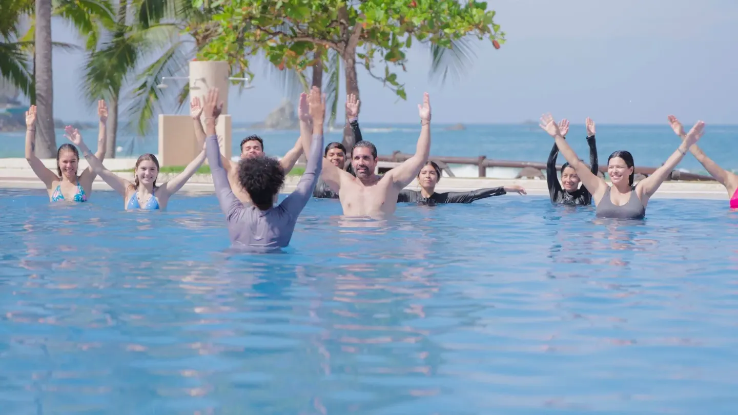 Guests raise their arms during a pool activity by the beach at Barceló Ixtapa.