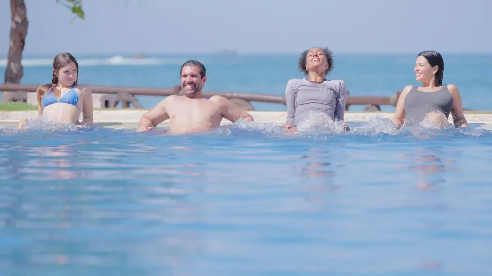 Guests relax at the pool edge with the ocean behind them at Barceló Ixtapa.