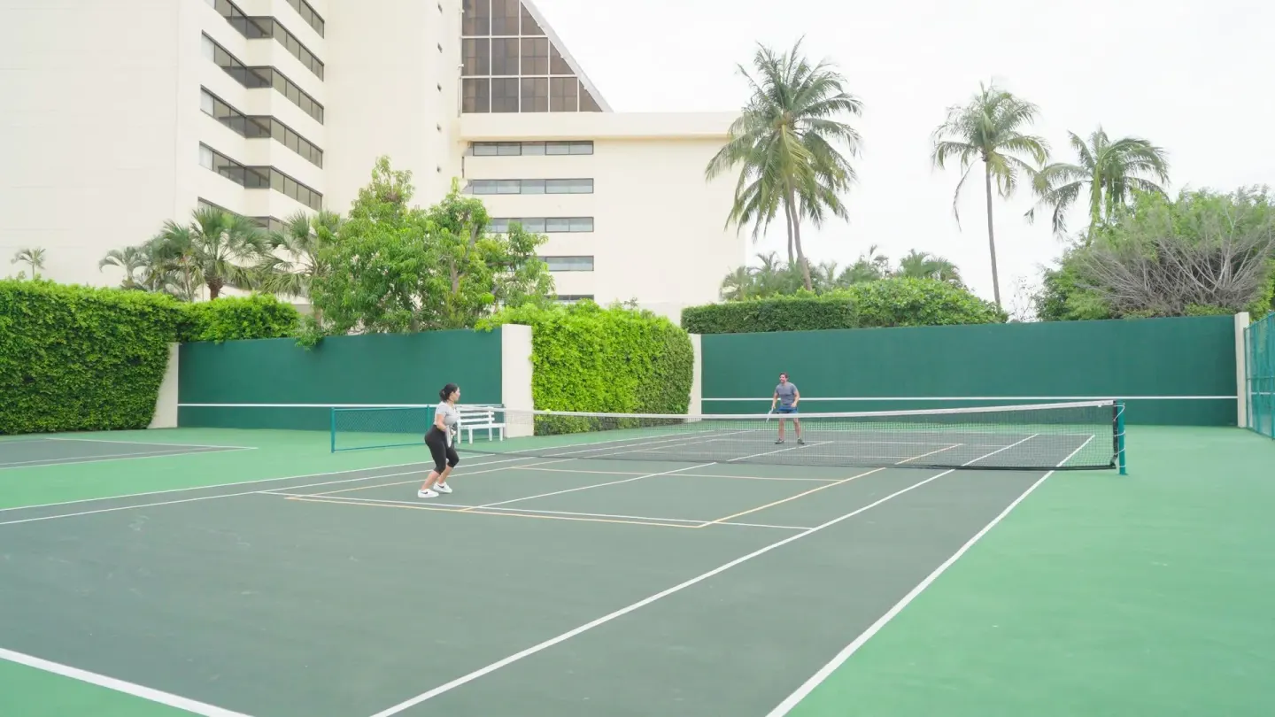 Guests play on the tennis court beside the resort building at Barceló Ixtapa.