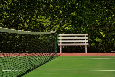 A tennis net and white bench sit beside a leafy hedge at Barceló Ixtapa.