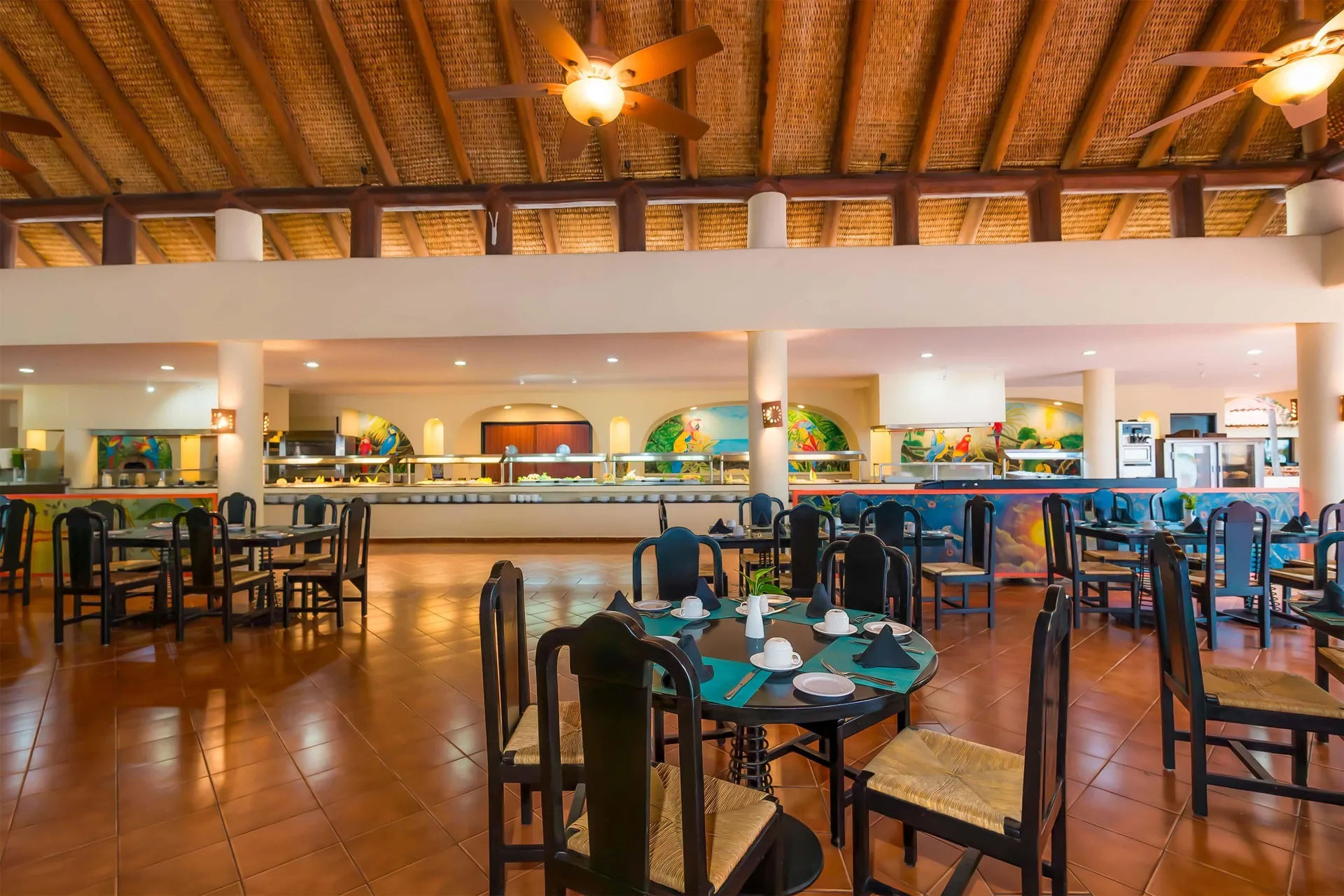 Buffet dining room with set tables and thatched ceiling at Barceló Ixtapa.