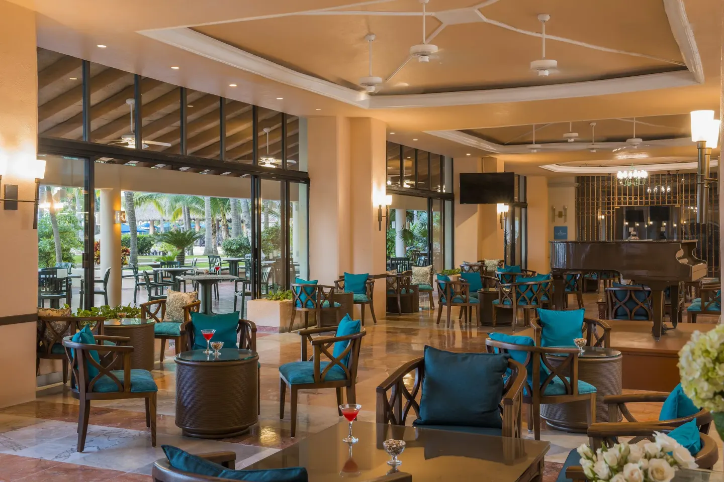 Lounge seating with turquoise cushions and a grand piano at Barceló Ixtapa.
