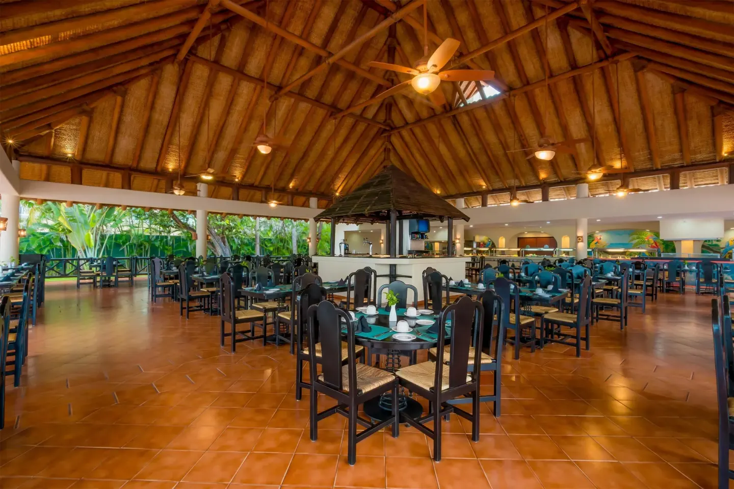 Open dining room with thatched roof and central service area at Barceló Ixtapa.