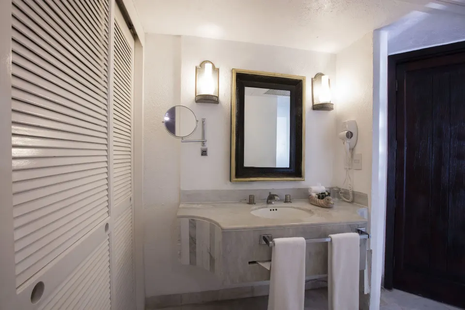 Family Villa bathroom vanity at Barceló Ixtapa with mirror, lights, towels, and closet doors.