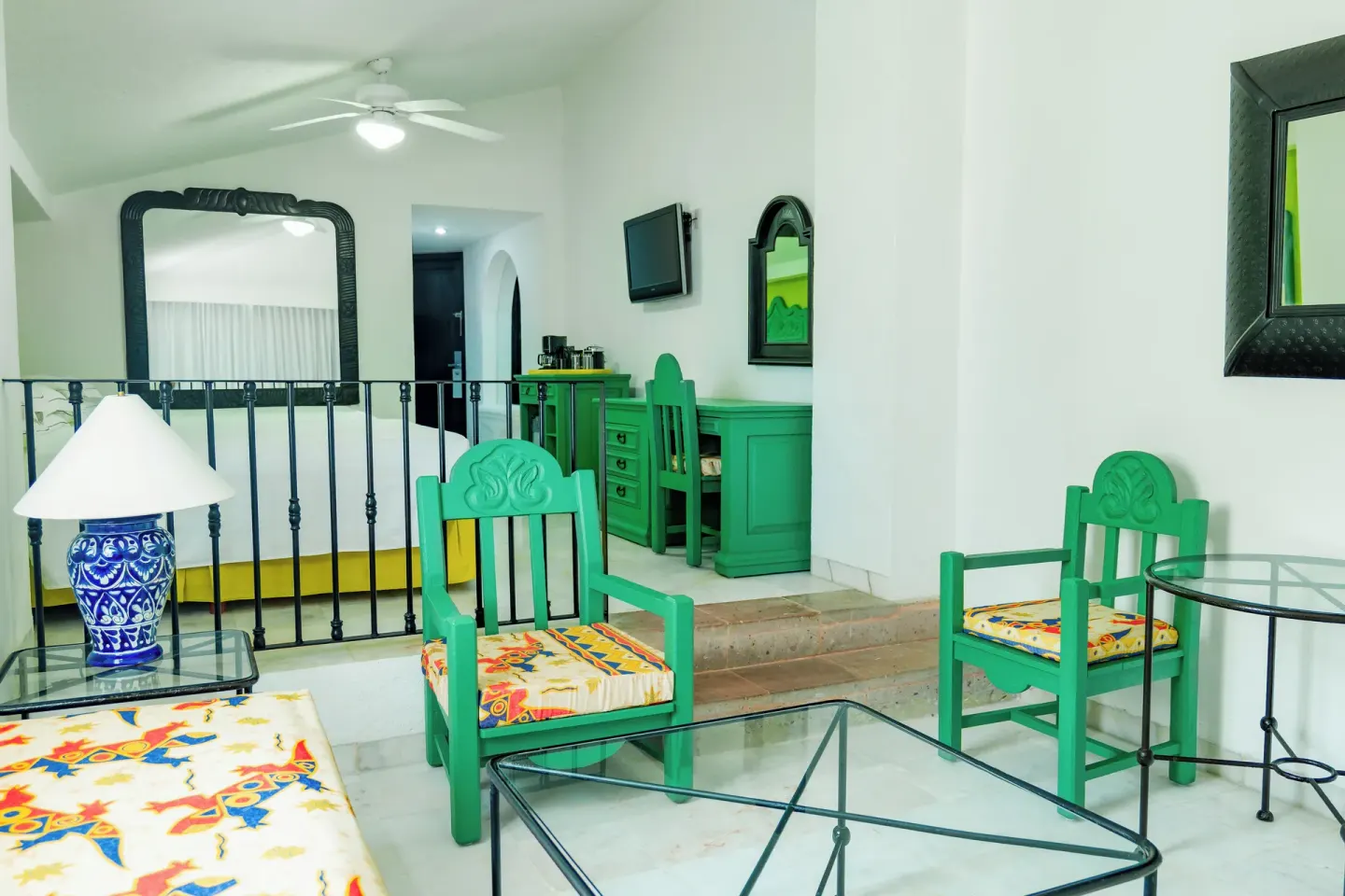 Family Villa sitting area with teal chairs, glass tables, and bedroom beyond at Barceló Ixtapa.