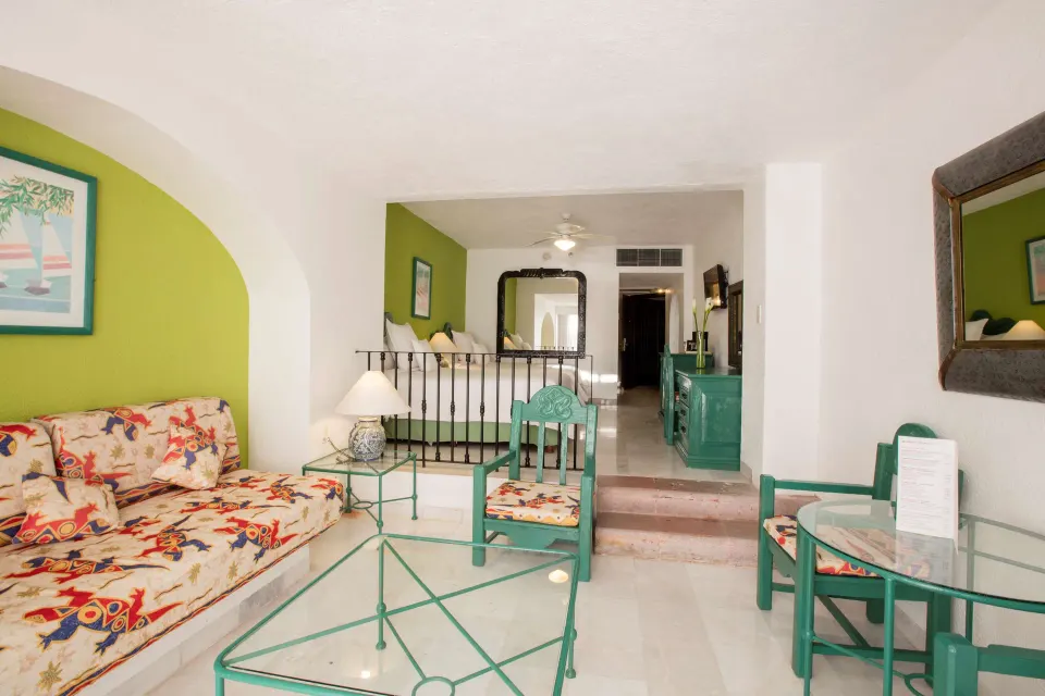 Family Villa sitting area with sofa, chairs, and bedroom beyond at Barceló Ixtapa.