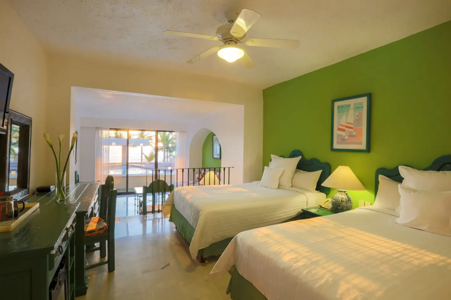 Family Villa bedroom with two double beds, desk, ceiling fan, and sliding doors at Barceló Ixtapa.