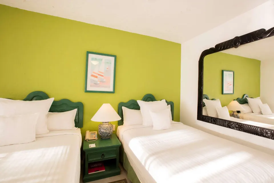 Family Villa two-bed sleeping area with green accent wall and large mirror at Barceló Ixtapa.