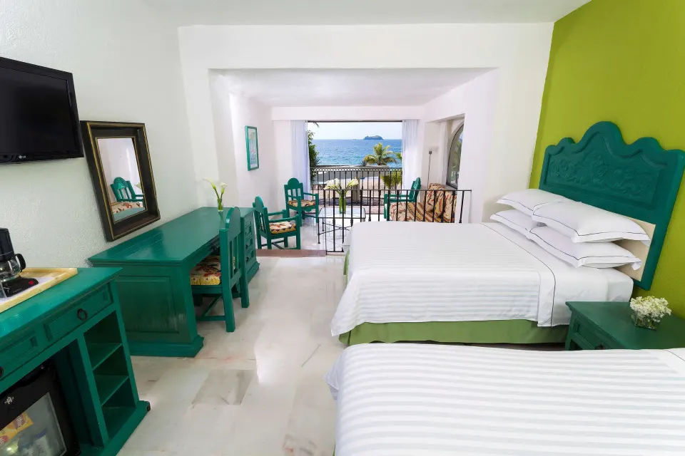 Family Villa room with two beds, teal furniture, and ocean balcony view at Barceló Ixtapa.