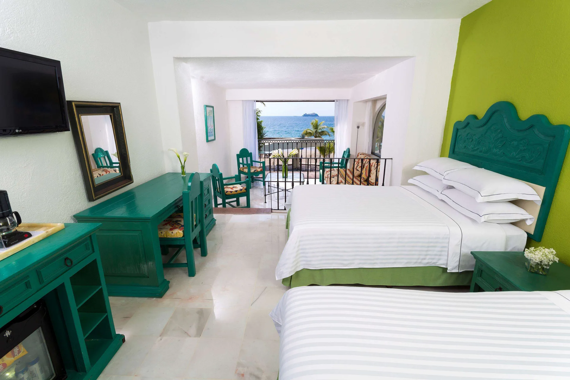 Family Villa room with two beds, teal furniture, and ocean balcony view at Barceló Ixtapa.