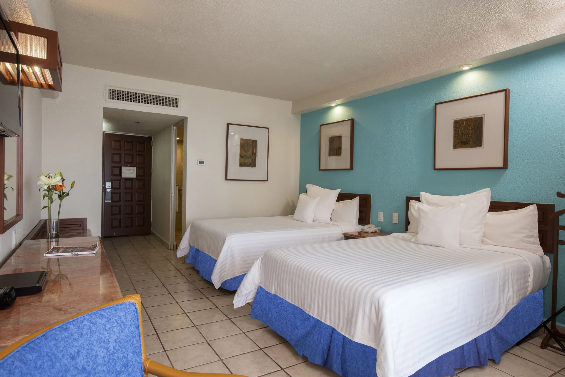 Superior Room Sea View with two beds, desk and turquoise wall at Barceló Ixtapa.