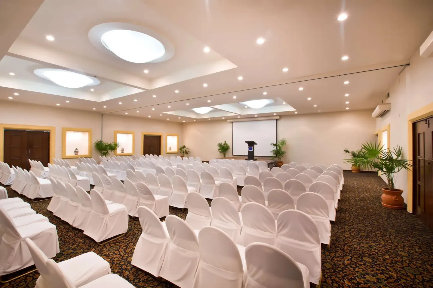 Theater-style meeting room with white chair covers and podium at Barceló Ixtapa.