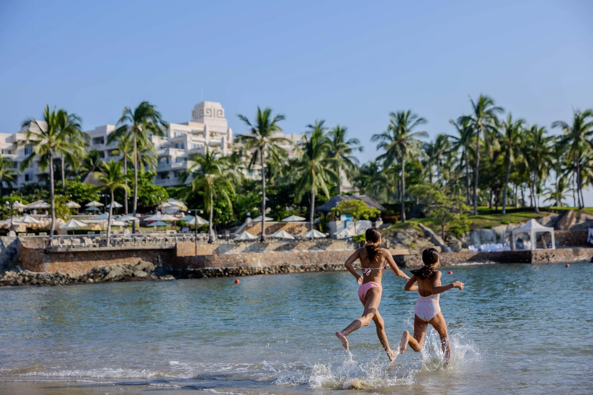 Two children run into the calm beach water at Barceló Karmina.