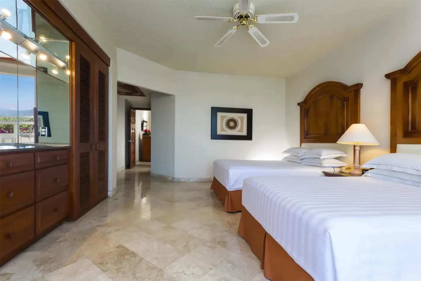 Guest room with two beds, wood cabinetry and mirrored vanity at Barceló Karmina.