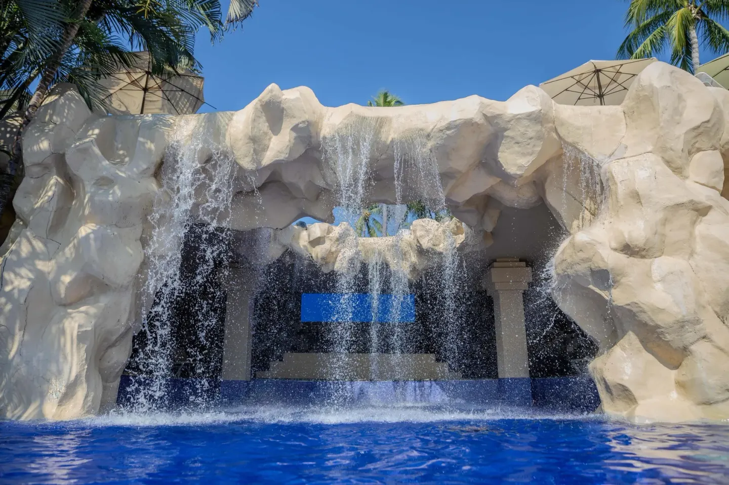 Rock-style waterfall feature flowing into a blue pool at Barceló Karmina.