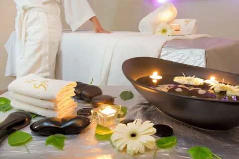 Spa treatment table with candles, flowers, towels, and hot stones at Barceló Karmina.