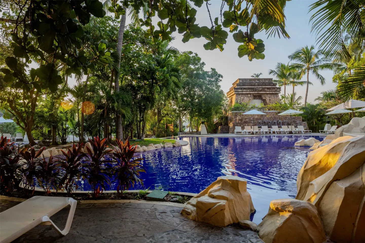 Tropical pool with loungers and rock features at Barceló Karmina.