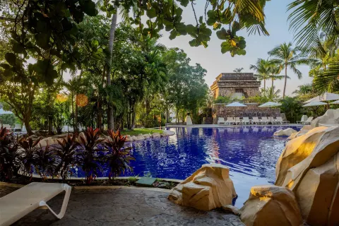 Tropical pool with loungers and rock features at Barceló Karmina.
