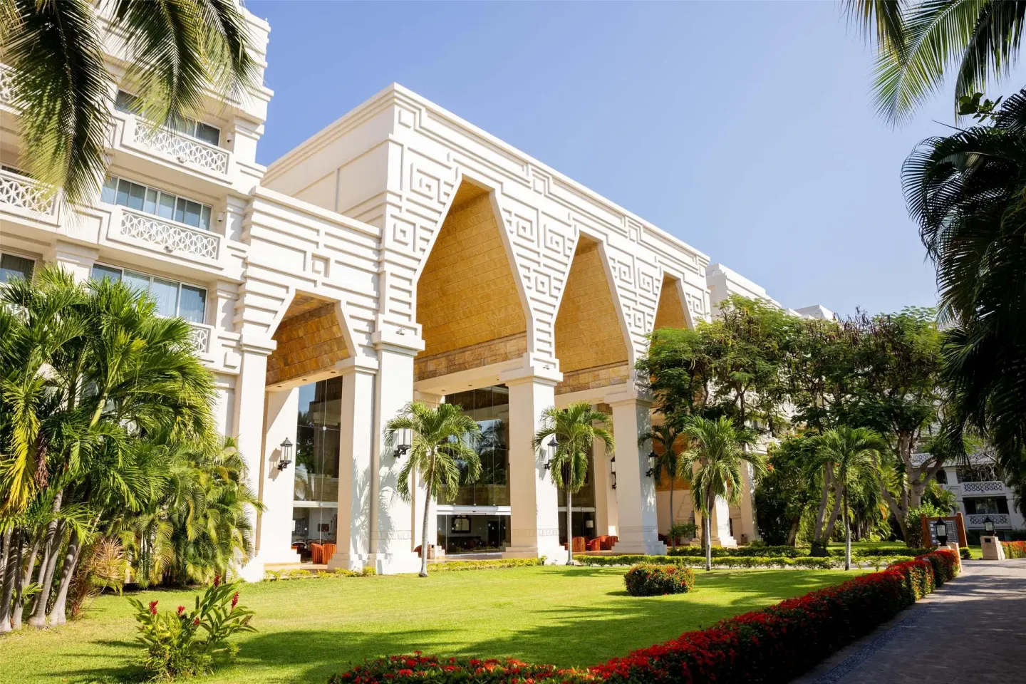 White resort facade, arched entrance and manicured gardens at Barceló Karmina.