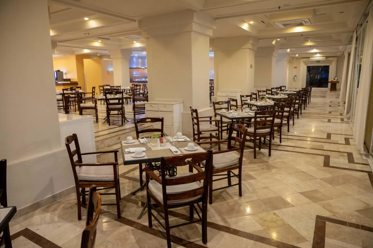 Indoor dining room with wooden chairs and marble floors at Barceló Karmina.