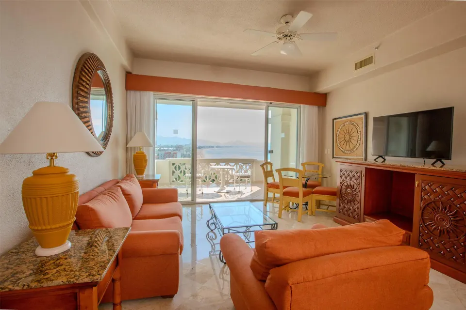 Junior Suite Premium Level lounge with orange sofas and TV at Barceló Karmina.
