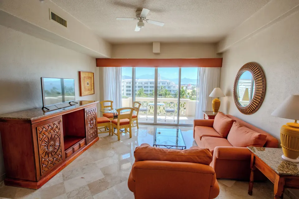 Junior Suite Sea View living area at Barceló Karmina with sofa, TV, dining table and balcony.