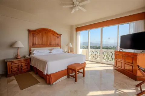 Master suite bedroom with king bed, balcony doors, and sea view at Barceló Karmina.