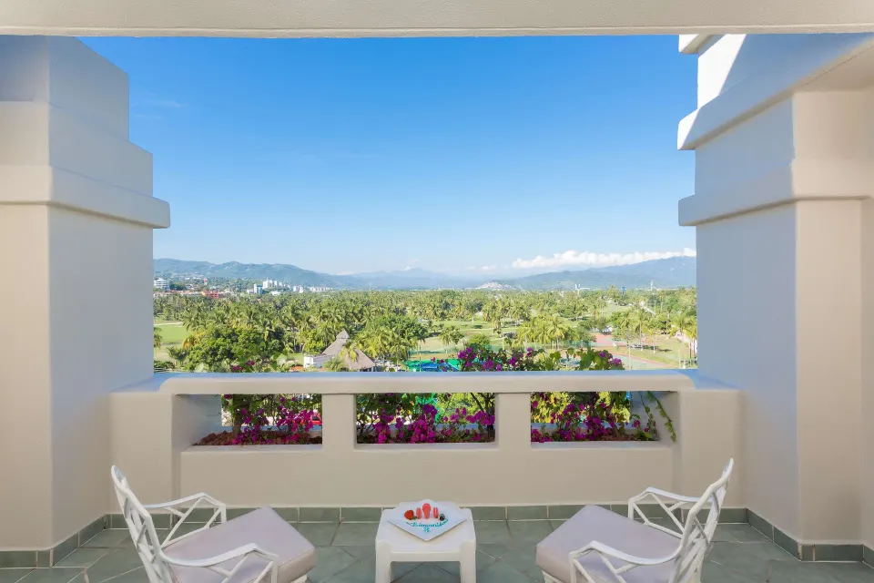 Suite Garden View terrace with lounge chairs and tropical landscape at Barceló Karmina.