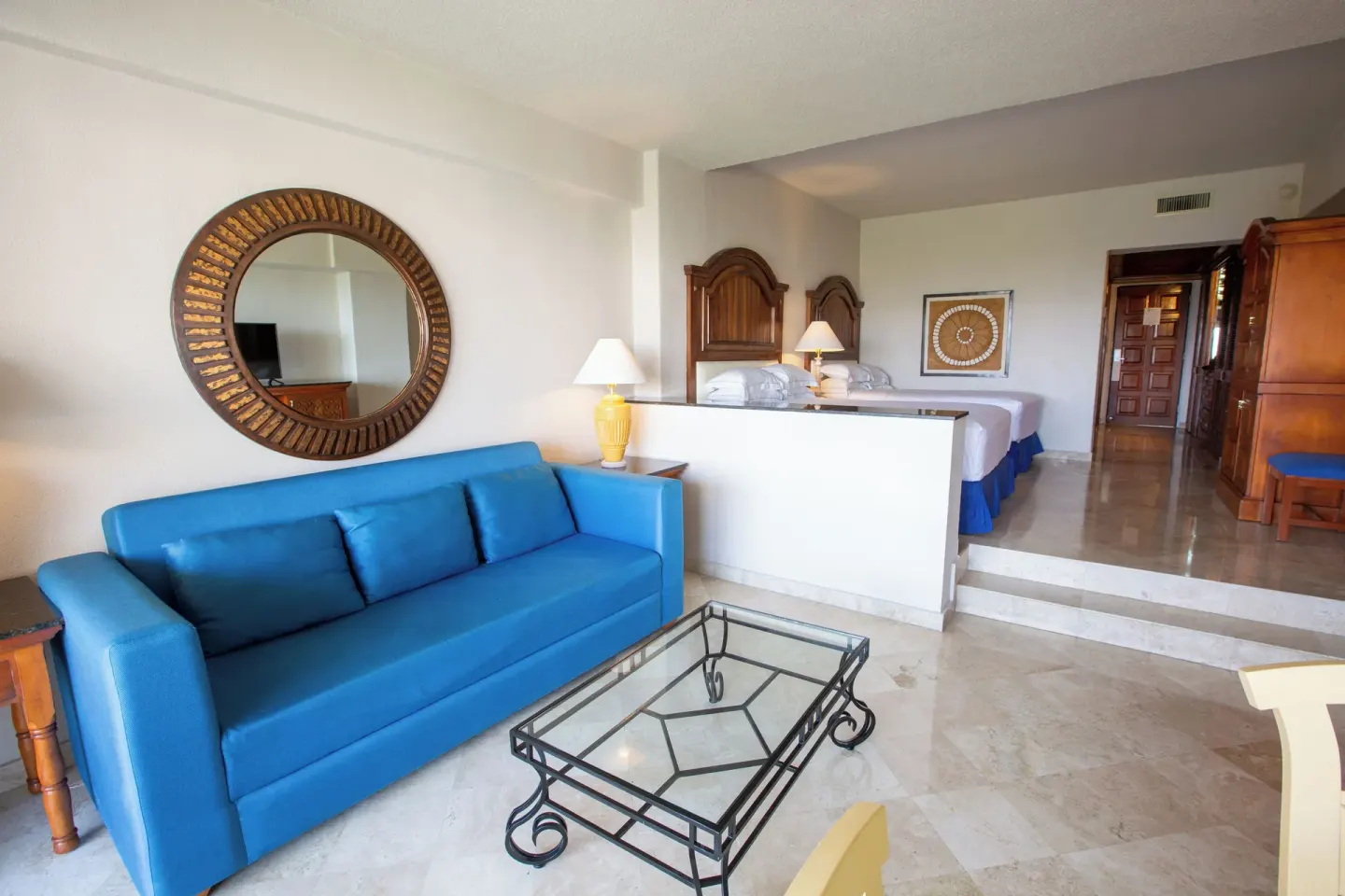 Suite Garden View living area with blue sofa and beds beyond at Barceló Karmina.