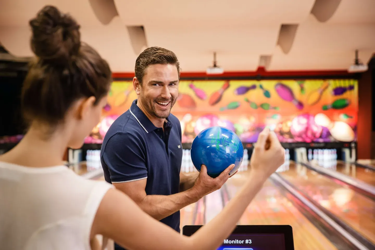 A guest holds a blue bowling ball near the lanes at Barceló Maya Caribe.